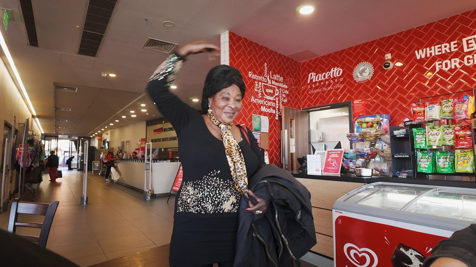 A woman dancing and waving in a leisure centre café in Barking and Dagenham